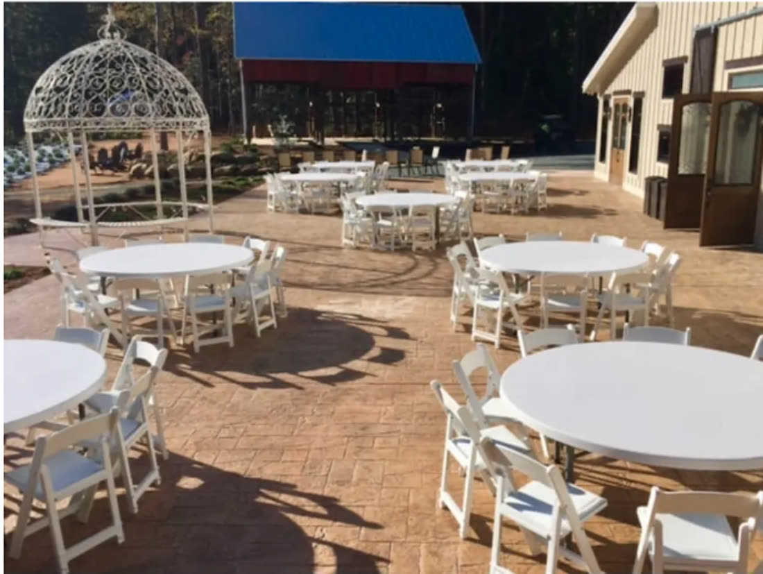 Round tables with white folding chairs set outdoors