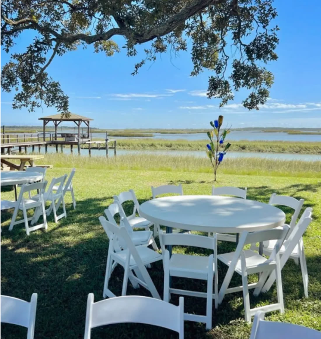 White padded resin chairs and round tables set for an outdoor gathering